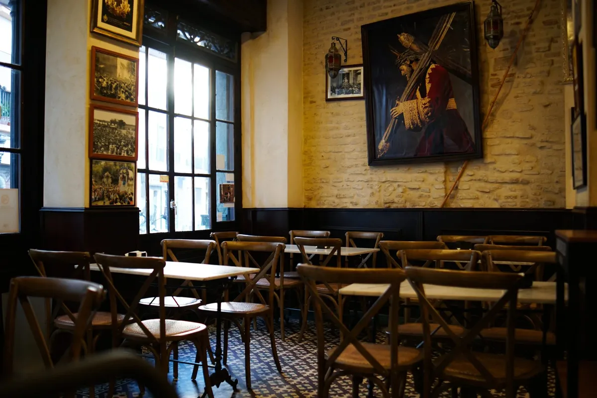 A cosy café room with wooden chairs, framed pictures and warm light